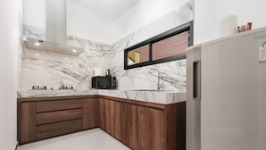 Una cocina moderna con encimeras de mármol, armarios de madera, horno integrado y refrigerador de acero inoxidable.