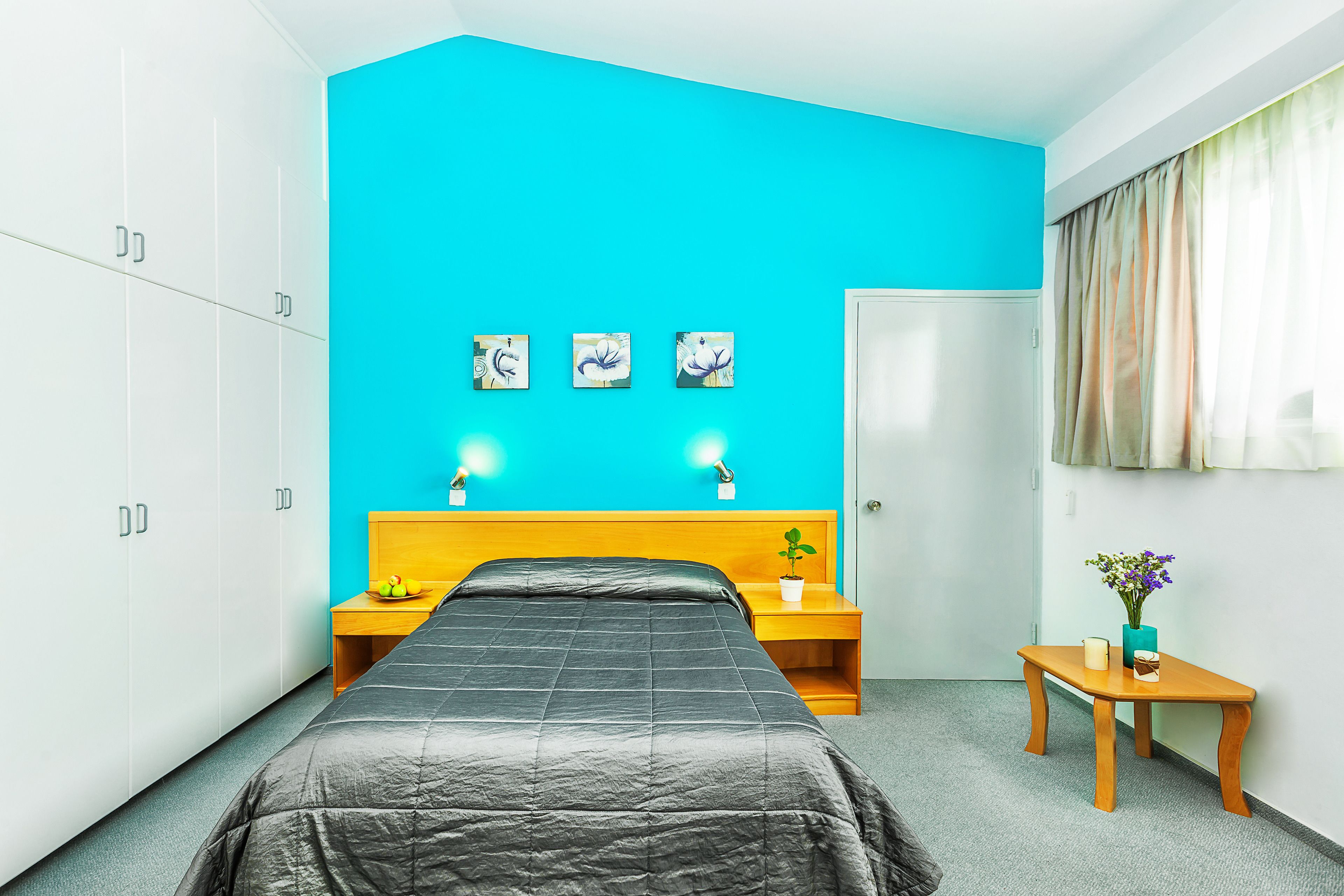 Un dormitorio con cama, mesita de noche, una pequeña mesa y una puerta.