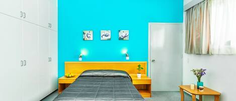 Un dormitorio con cama, mesita de noche, una pequeña mesa y una puerta.