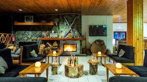A cozy lounge area with sofas, wooden tables, and a fireplace. - Troodos Hotel (Troodos)
