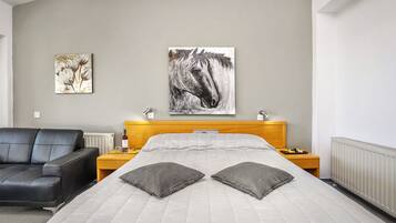 A hotel room with a bed, a nightstand, a chair, and two wall art pieces.
