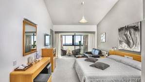 A hotel room with a bed, desk, chair, and a large window offering a mountain view. - Troodos Hotel (Troodos)
