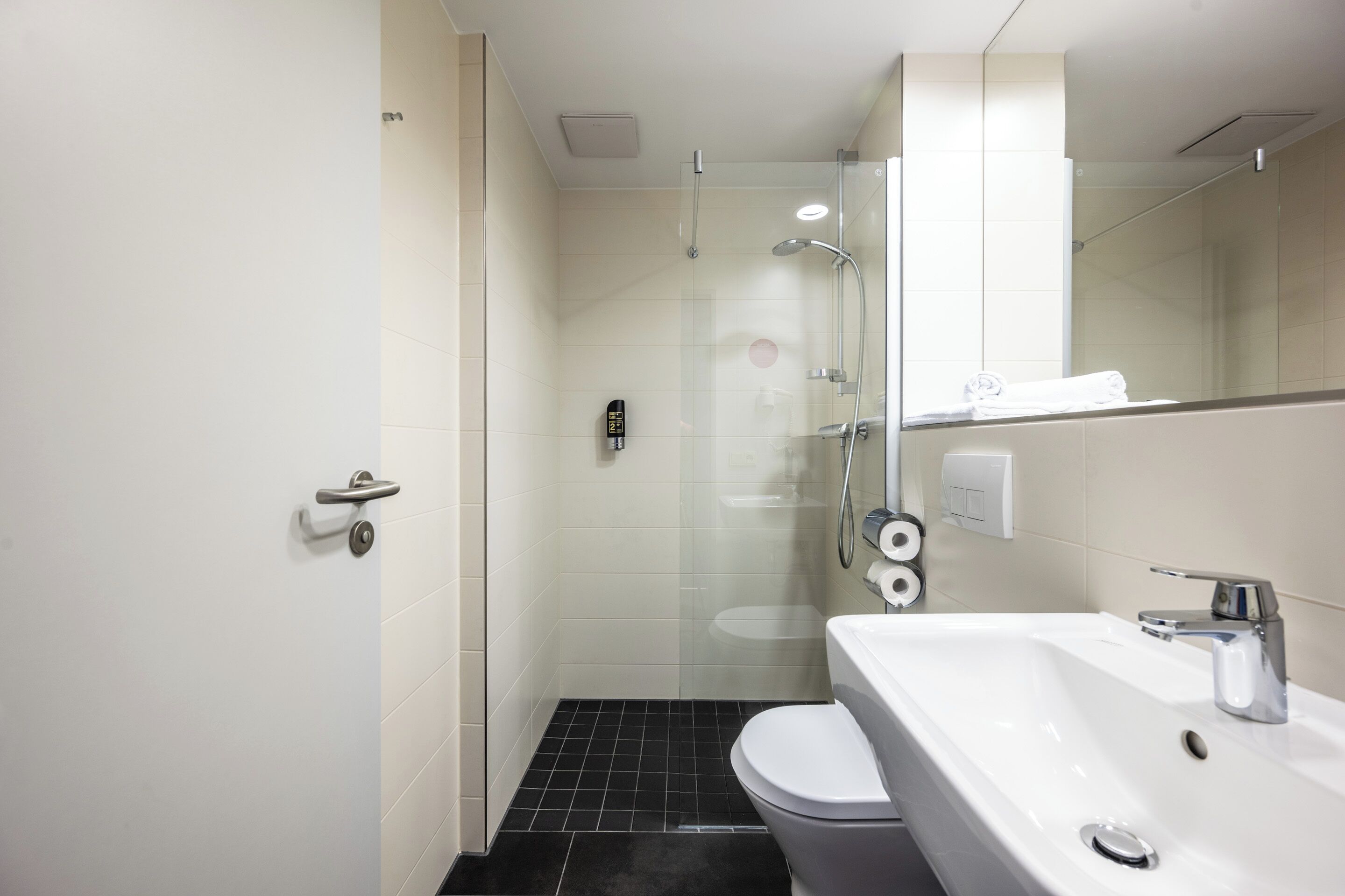 A modern bathroom with a white sink, a toilet, and a glass-enclosed shower area.