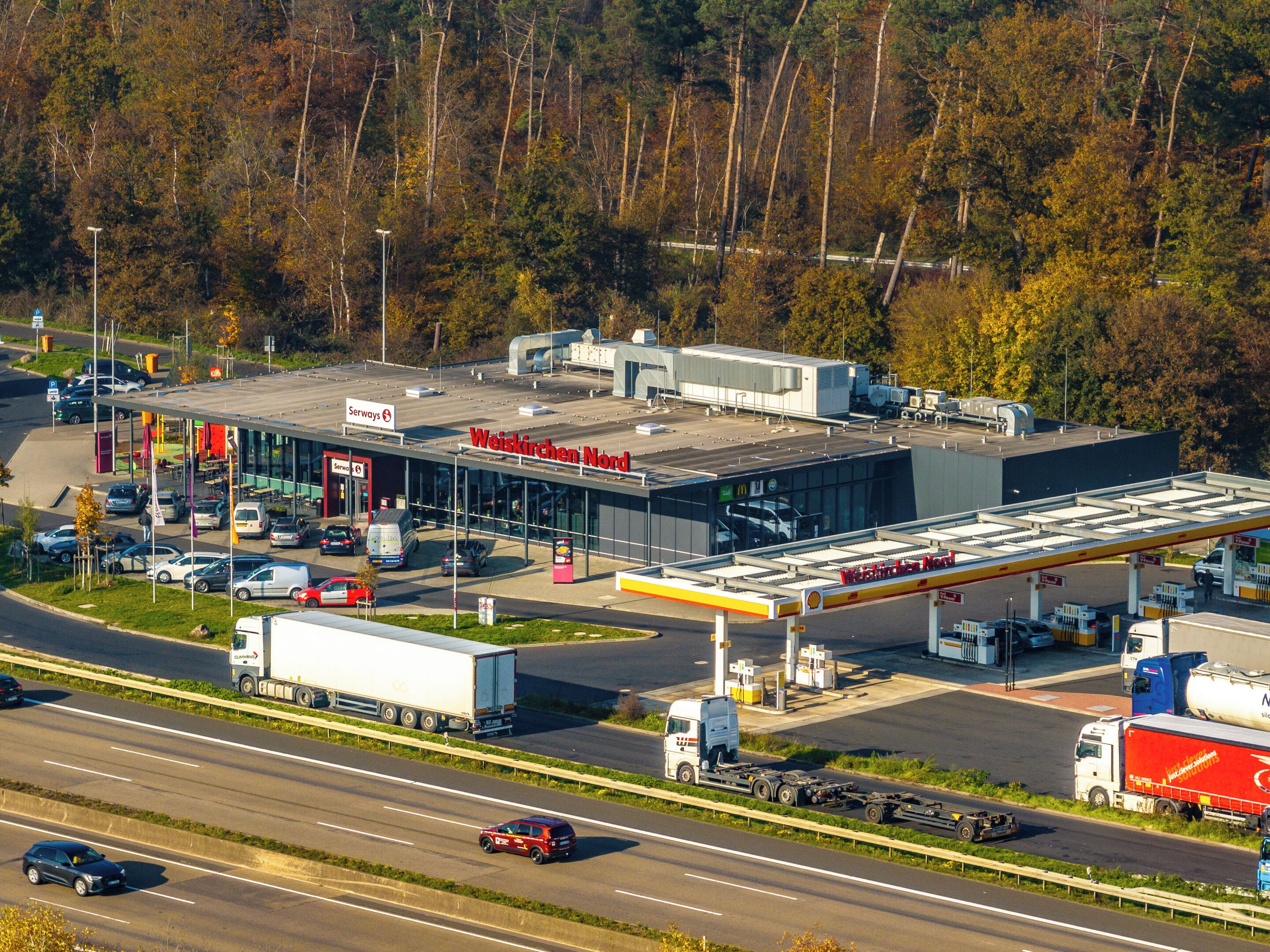 Una estación de servicio Weiskirchen Nord con un edificio grande, varias bombas de combustible y un área de estacionamiento.