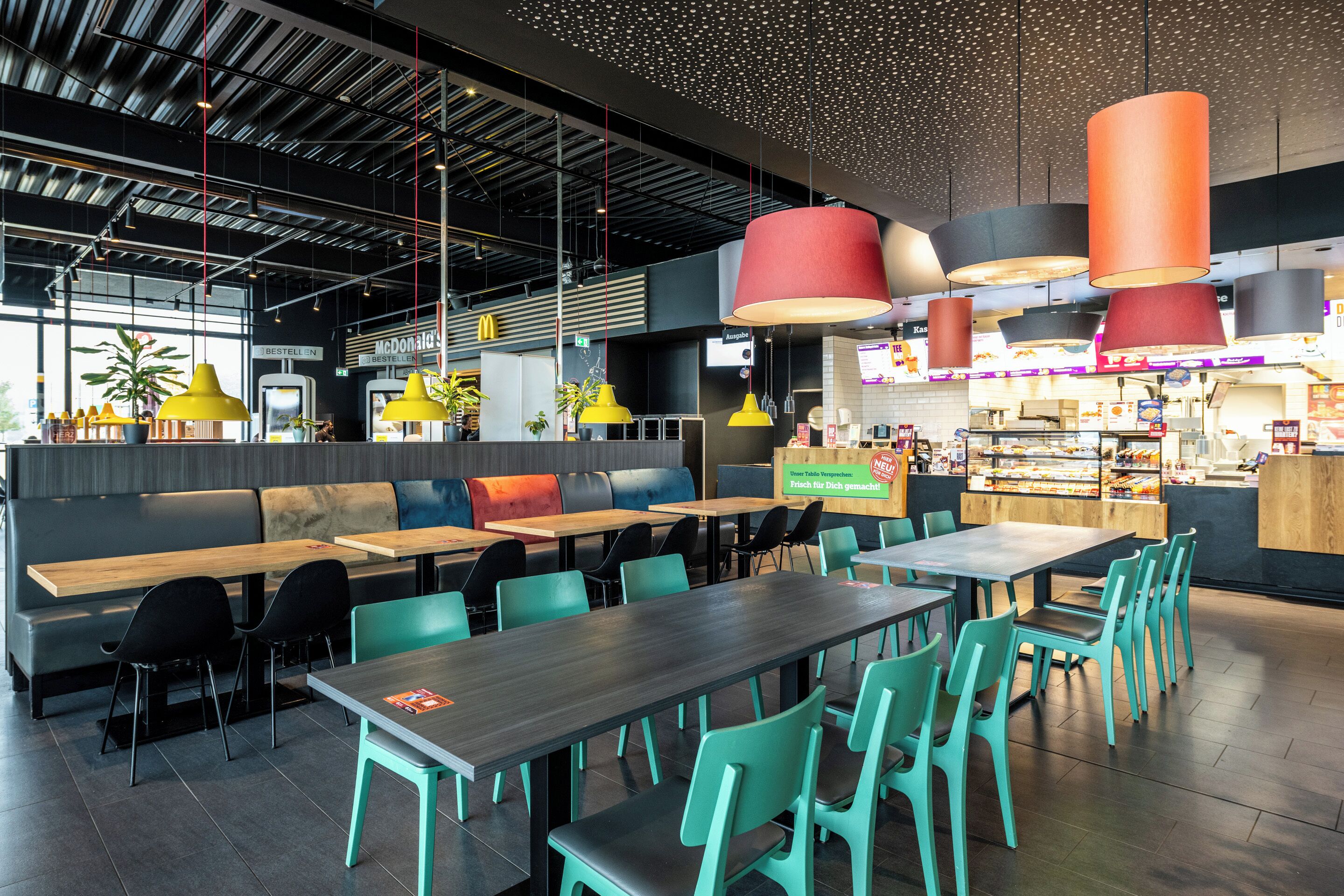 A modern restaurant with high ceilings, multiple seating areas, and a variety of table and chair arrangements.