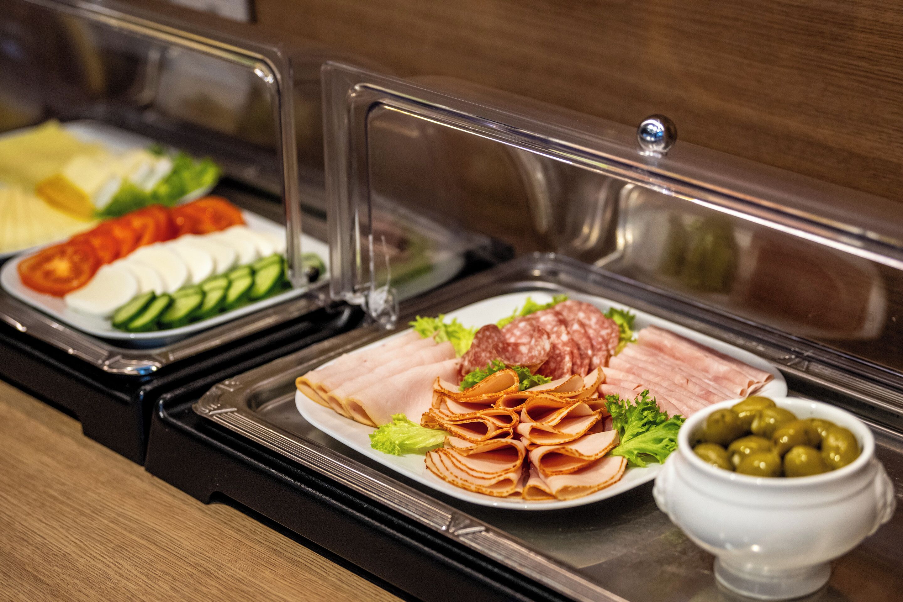 A buffet with various food items including sliced meats, cheeses, and vegetables.
