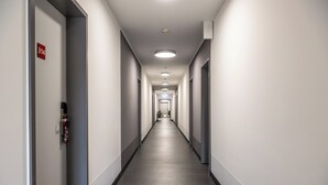Un largo y estrecho pasillo de hotel con puertas a ambos lados, un detector de incendios a la izquierda y un cartel que indica la habitación 314.