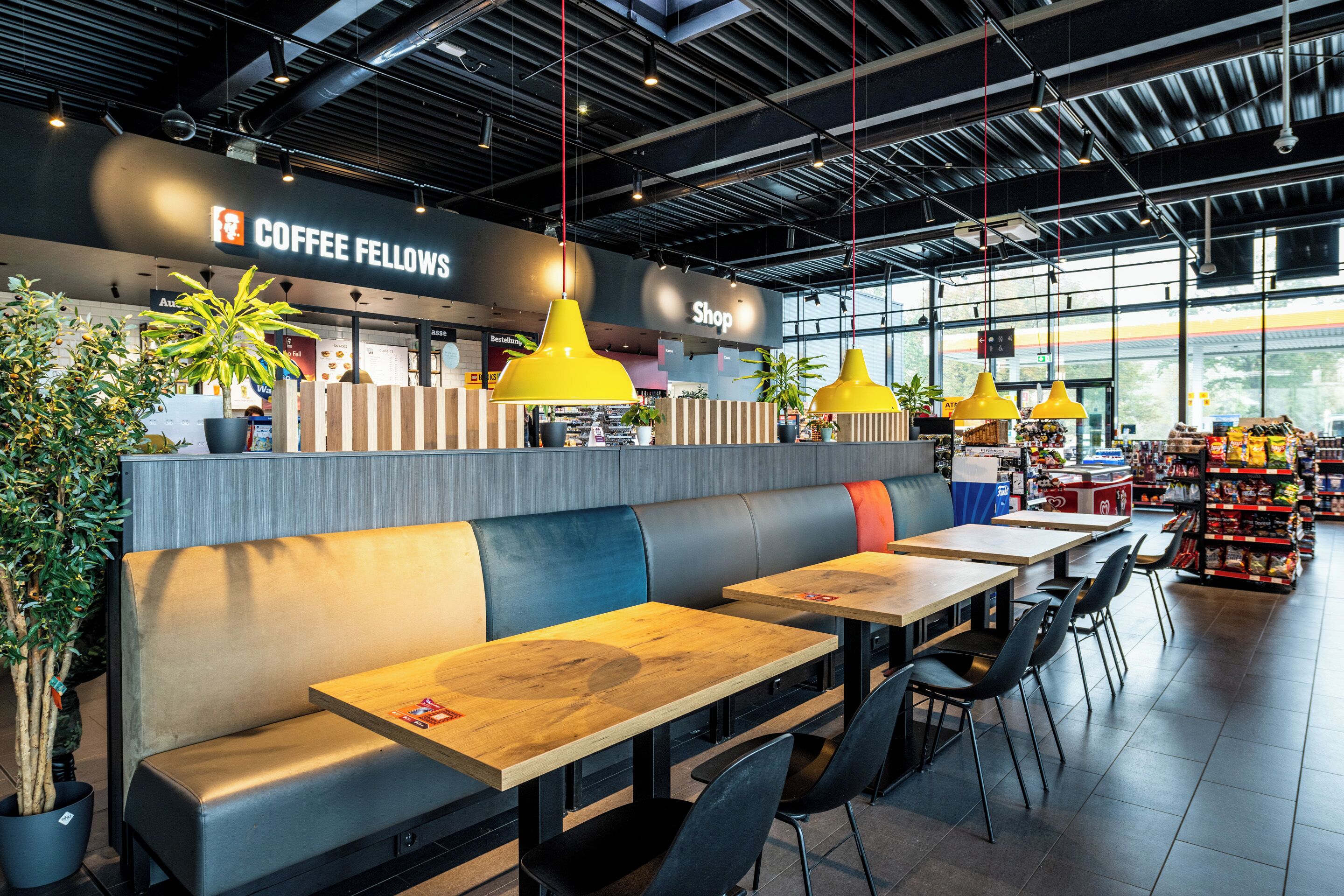 Un interior de cafetería moderna con asientos, una barra y vistas al exterior.