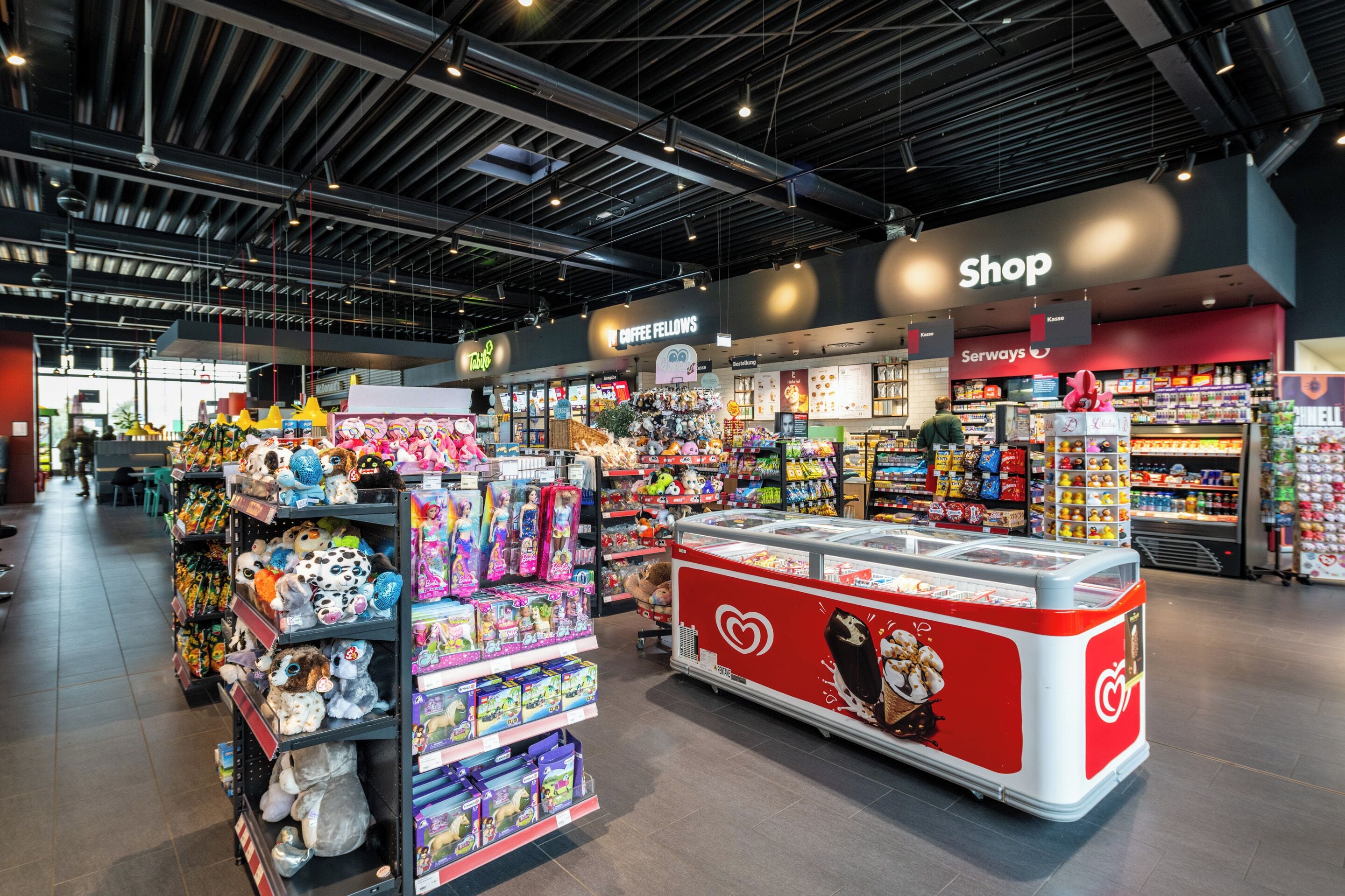 A modern retail store with various sections including a shop, coffee, and Serways.