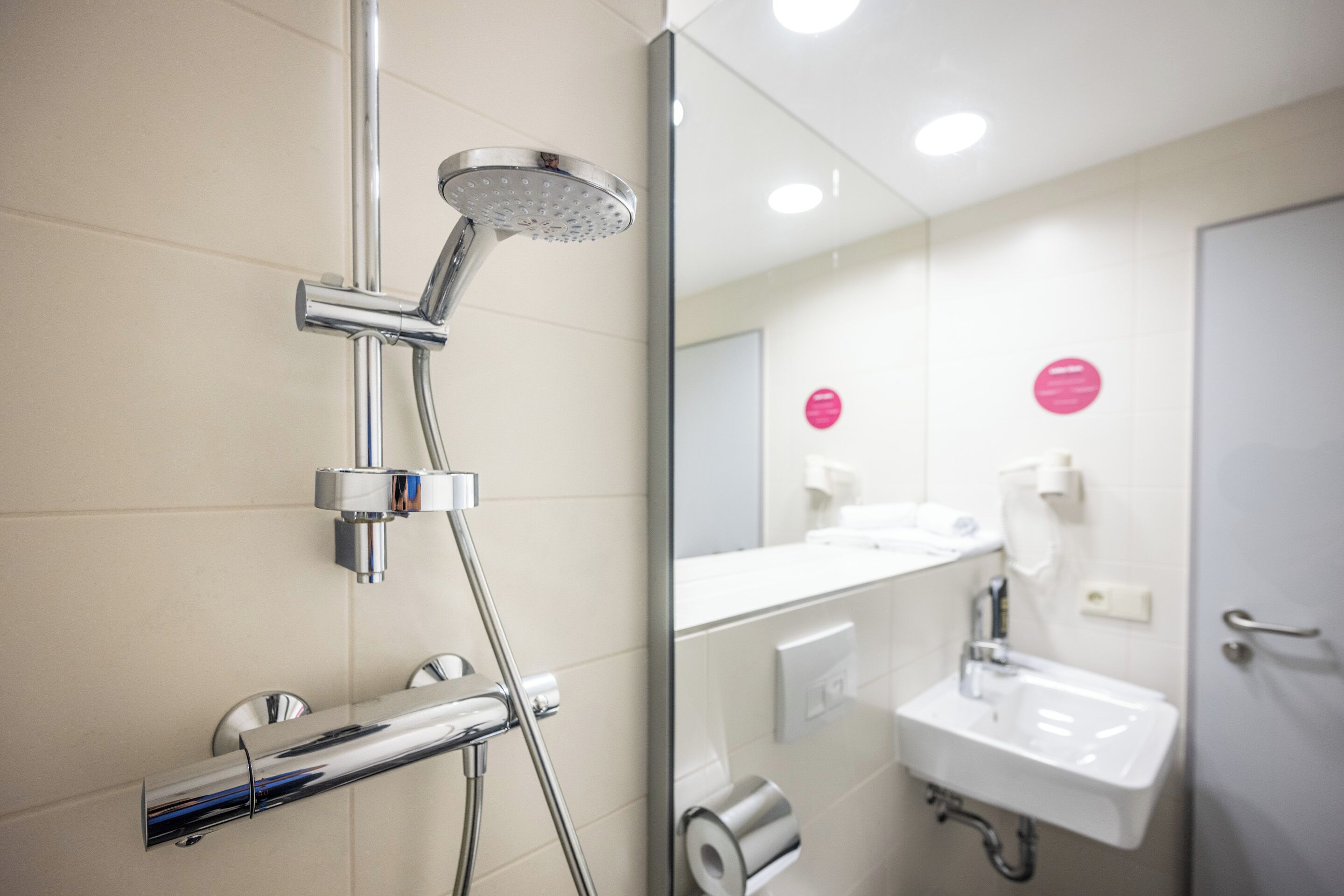 A modern bathroom with a chrome shower, a sink, and a toilet.