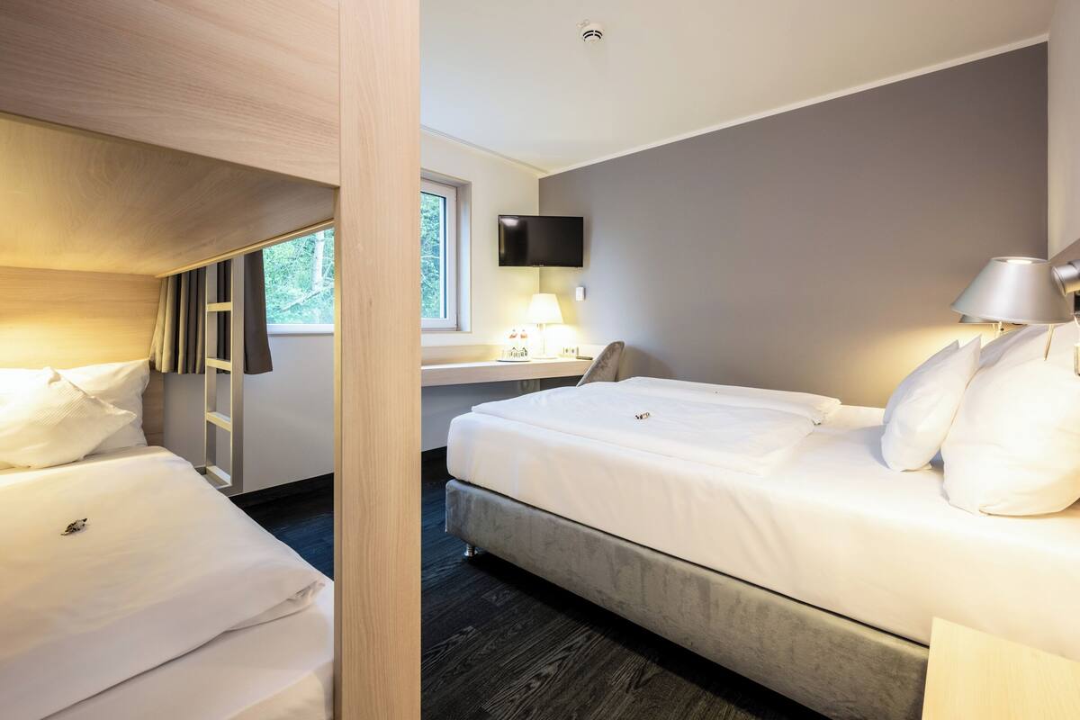 Hotellihuone, jossa on kaksi sänkyä, työpöytä, televisio ja ikkuna.