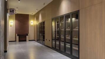 A hallway with a bench, wooden panel walls, and glass display cabinets.