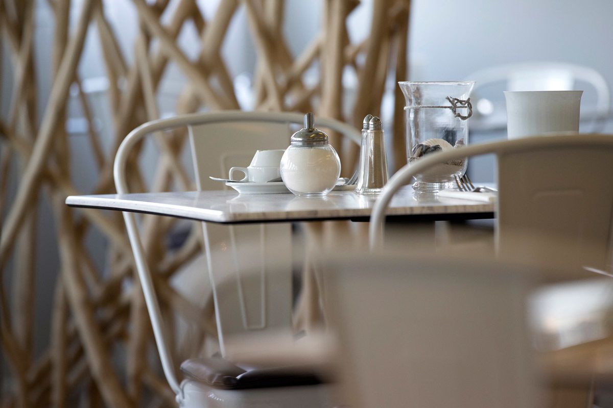 Ein Tisch mit Teekanne, Zuckerbehälter, Salzer und einem Glas Wasser.