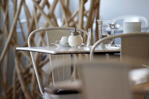 Una mesa con un hervidor blanco, un azucarero, un salero y un vaso de agua.