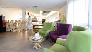 A modern interior with green and purple chairs, a glass table with a decorative item, and a white sculpture. - Nautic Hotel Bremerhaven (Bremerhaven)