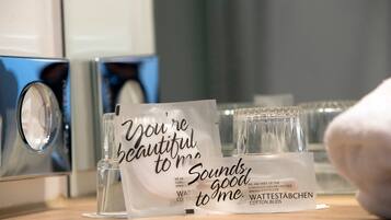 Una zona de recepción de hotel con una tarjeta de mensaje que dice “Eres hermoso/a para mí. Suena bien”. Y un vaso de agua.