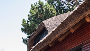Een vakantiehuis in blokhutstijl met een terras, grote schuifpuien en een bordje dat een open kantoorruimte aangeeft.