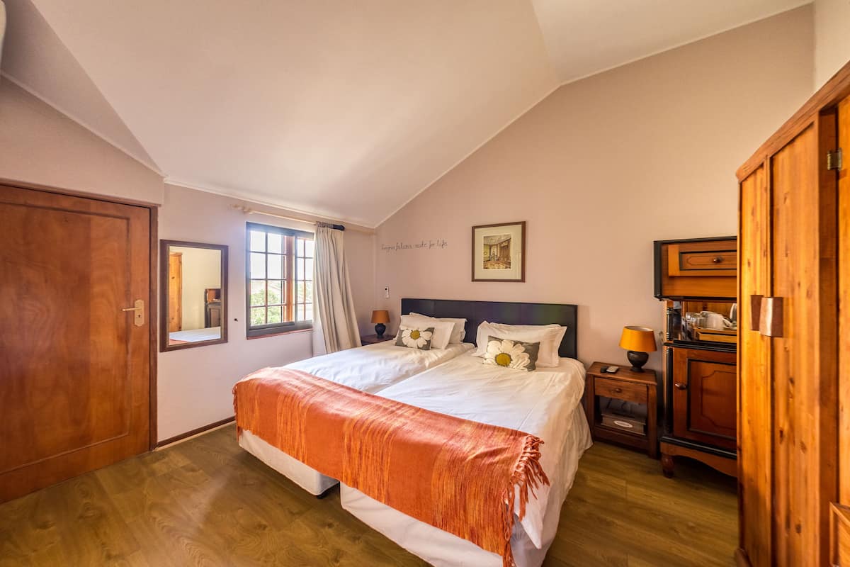 A bedroom with a double bed, a wooden wardrobe, a nightstand, and a window with curtains.