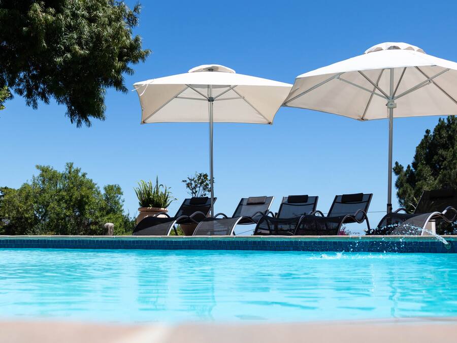 Una piscina al aire libre, sillones reclinables de piscina