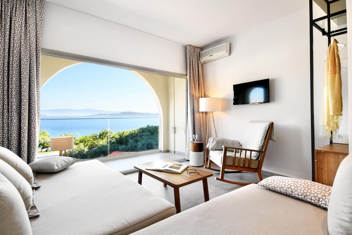 Ein modernes Hotelzimmer mit großem Fenster und einem schönen Blick auf das Meer und die Berge.