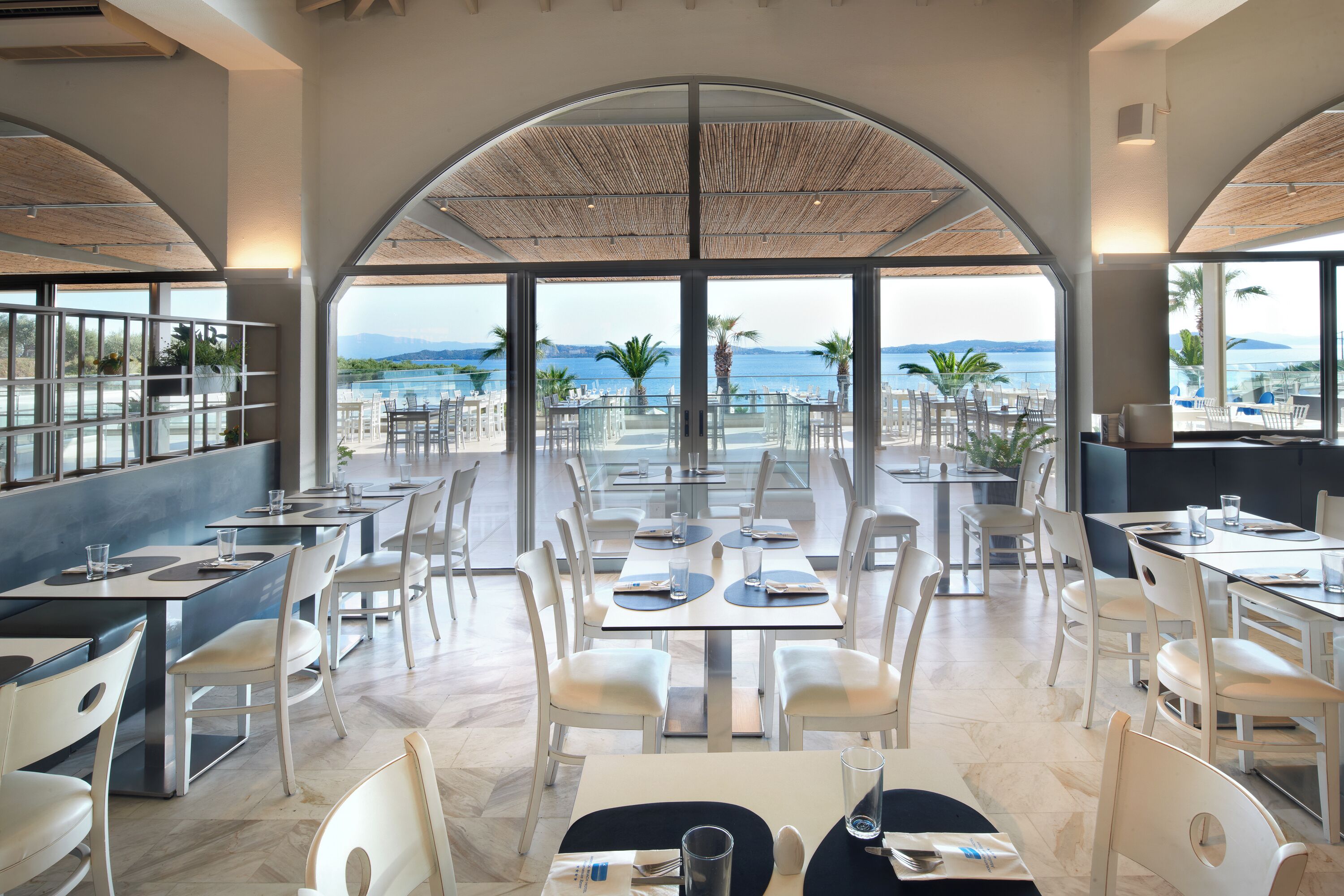 Un restaurante con vista al mar, con mesas y sillas dispuestas para comer.