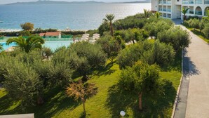 Um resort com piscina, vegetação exuberante e vista para o mar.