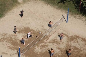 A sandy beach volleyball court with a net, surrounded by people playing. - Serenis Hotel - All Inclusive (Manavgat)