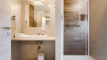 A modern bathroom with a sink, mirror, hairdryer, and shower.