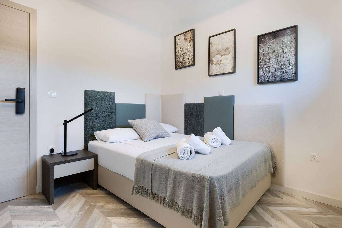 A modern bedroom with a bed, bedside tables, and artwork on the walls.