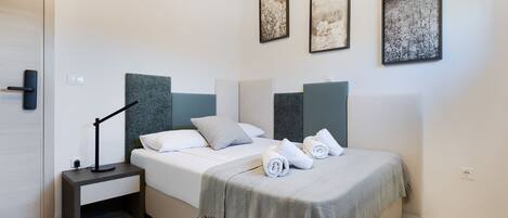 A modern bedroom with a bed, bedside tables, and artwork on the walls.