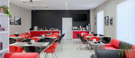 Una habitación de hotel moderna con zona de comedor, espacio privado y televisor montado en la pared.