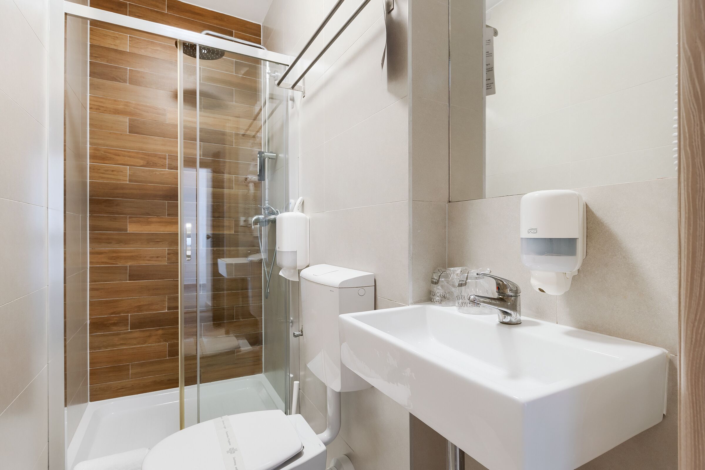 A modern bathroom with a glass shower enclosure, a white sink, and a toilet.