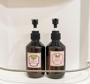 Two bottles of shampoo and shower gel on a white shelf. - 26 Bed and Coffee (Chonburi)