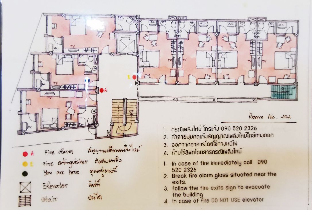 Planta baixa de um quarto de hotel com comodidades como televisão, alarme de incêndio e extintor.