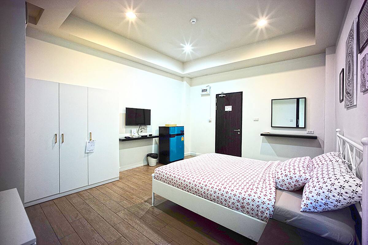 Un dormitorio con cama, armario, escritorio y espejo en la pared.