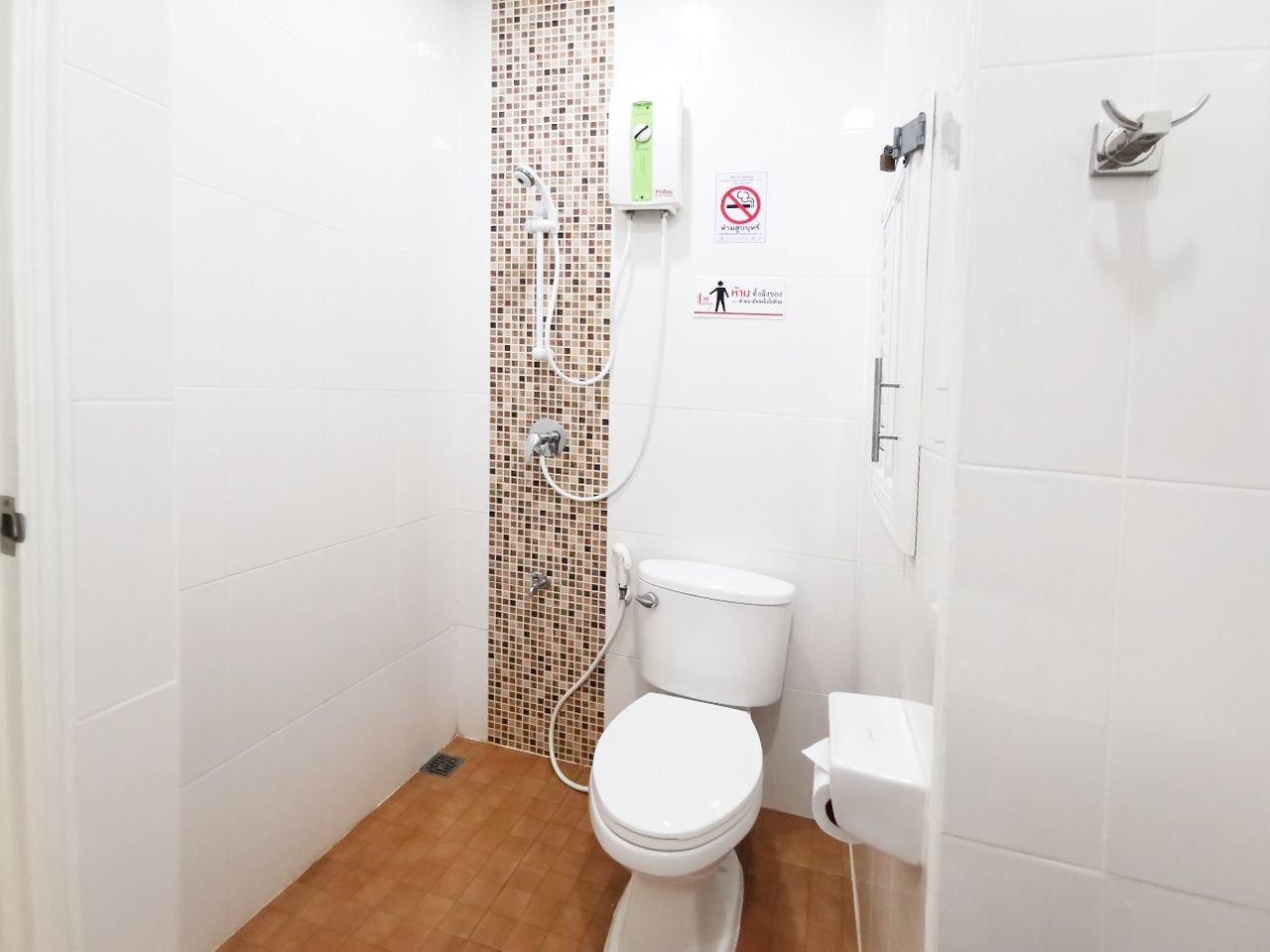 A small, compact bathroom with a toilet, a shower, and a sink.