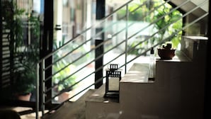 A staircase with a view of greenery outside, a small table with a potted plant, and a decorative lantern. - 26 Bed and Coffee (Chonburi)
