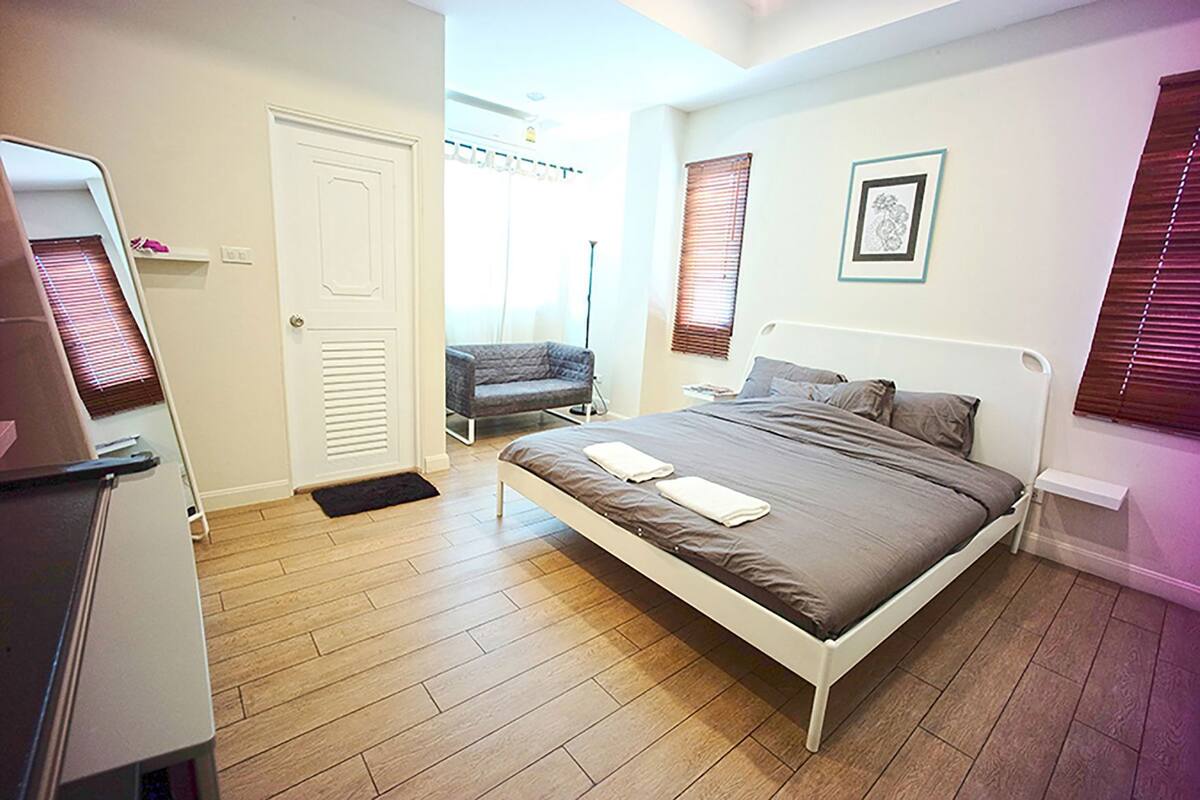 Un dormitorio con cama, una silla, una puerta y una ventana.