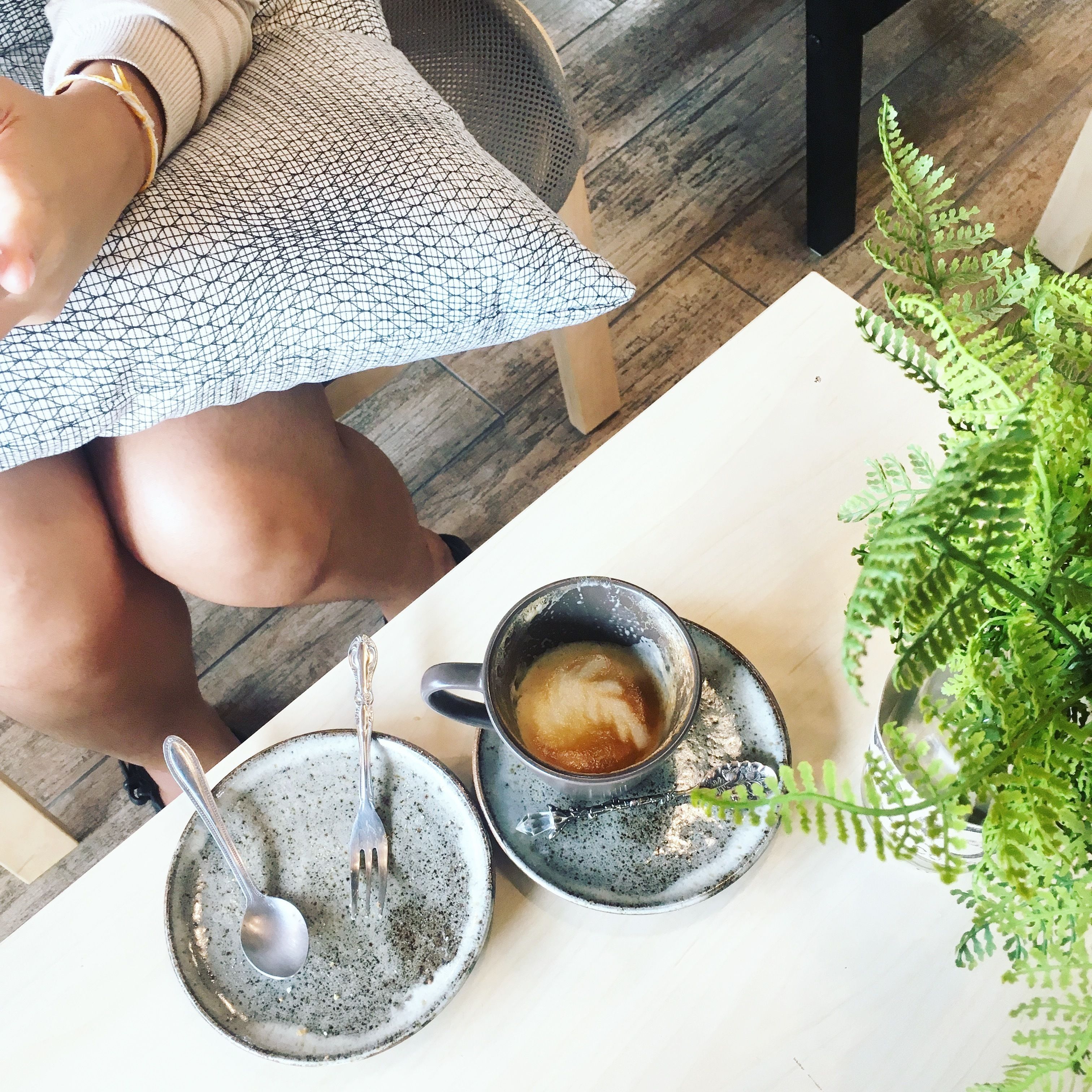 A table with a cup of coffee, a spoon, and a saucer.