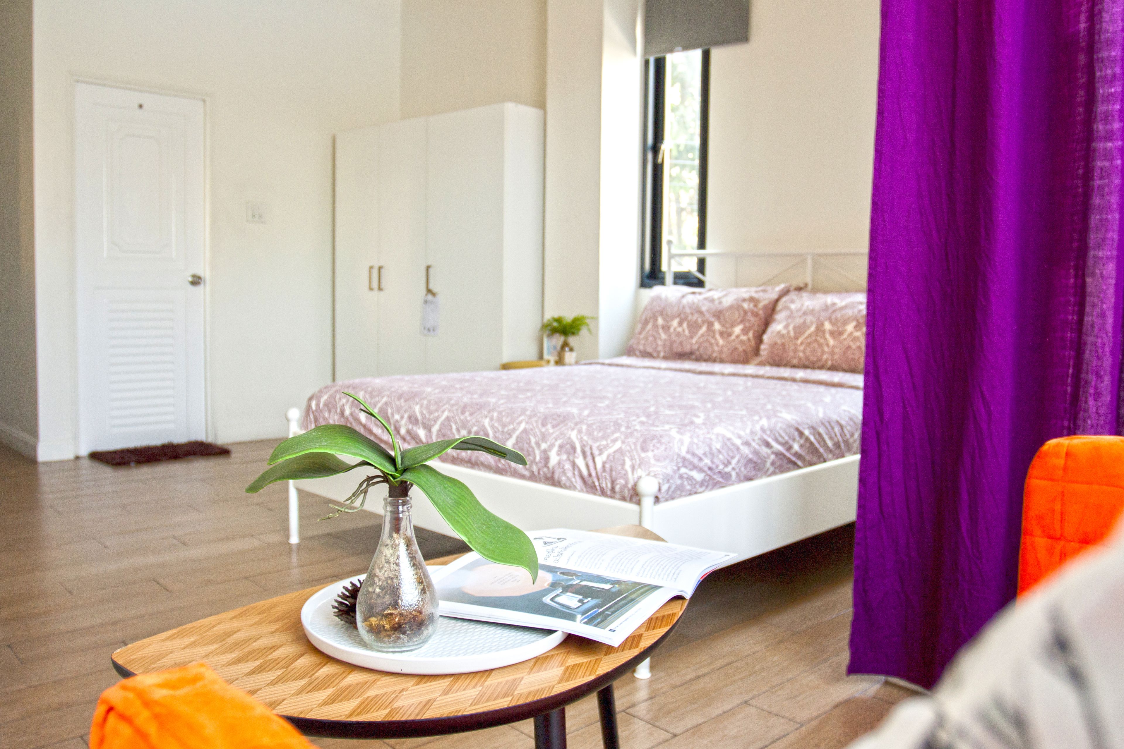A bedroom with a bed, a nightstand, a window, and a door.