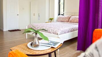 A bedroom with a bed, a nightstand, a window, and a door.