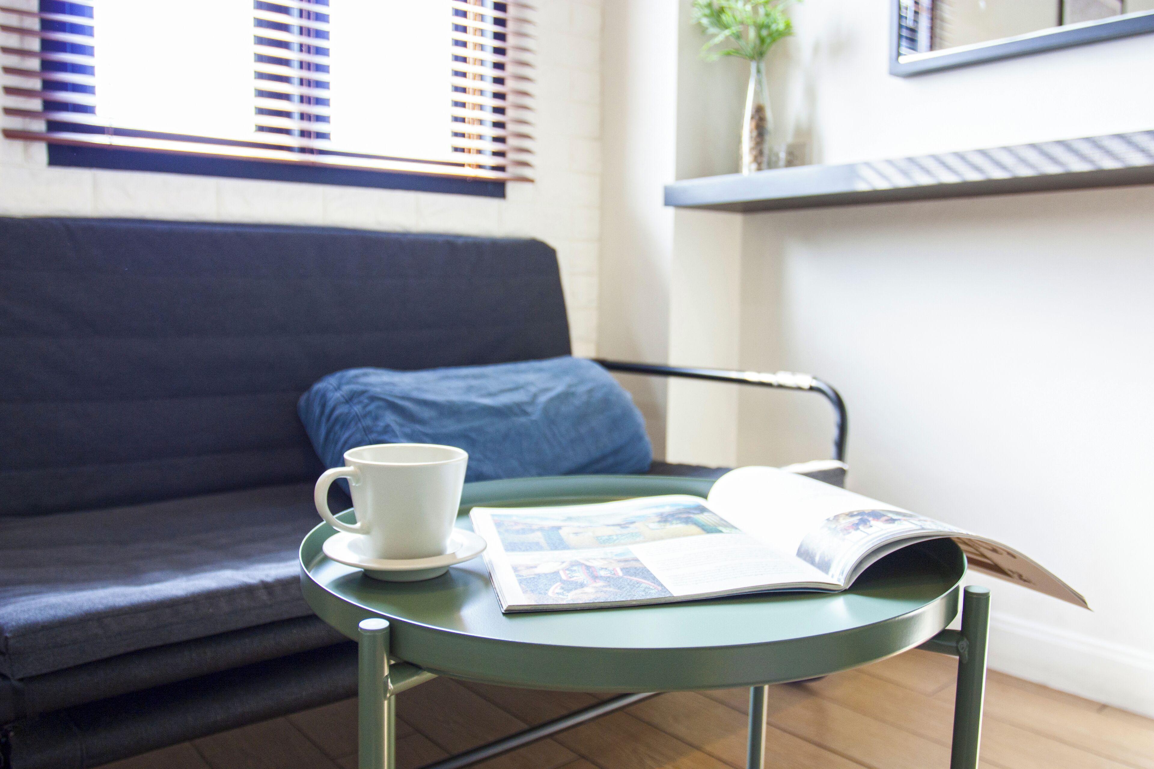 A room with a green table, a white cup, and a magazine.