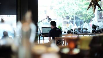 Eine Person arbeitet an einem Schreibtisch mit einem Laptop, einer Lampe und einer Stern-Dekoration in einem Zimmer mit einem Fenster.