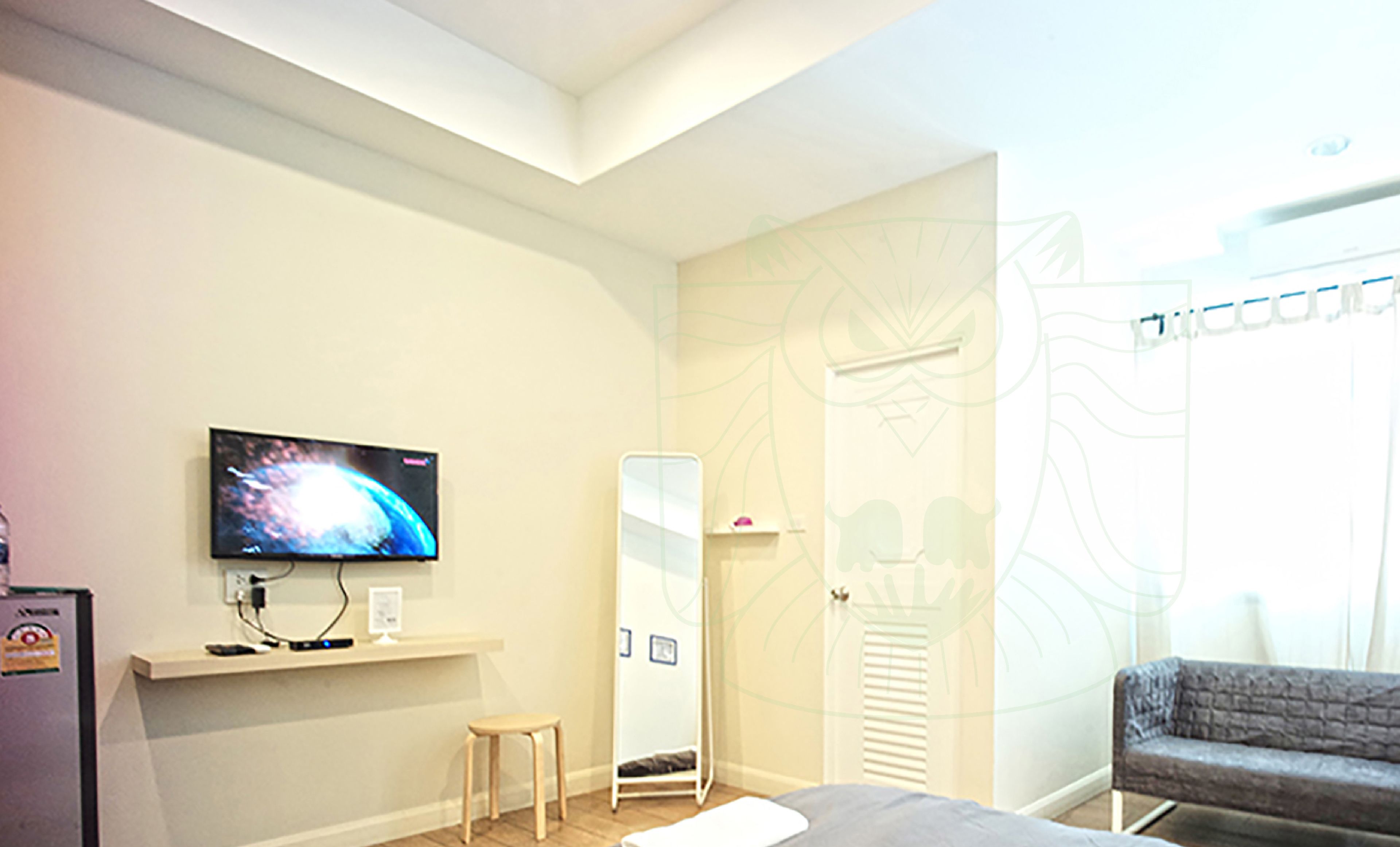 A hotel room with a bed, a TV, a small stool, a wardrobe, and a chair.