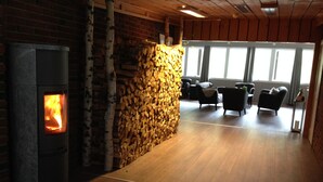 Una habitación con estufa de leña, pared de piedra y zona de estar con sillas y una mesa.