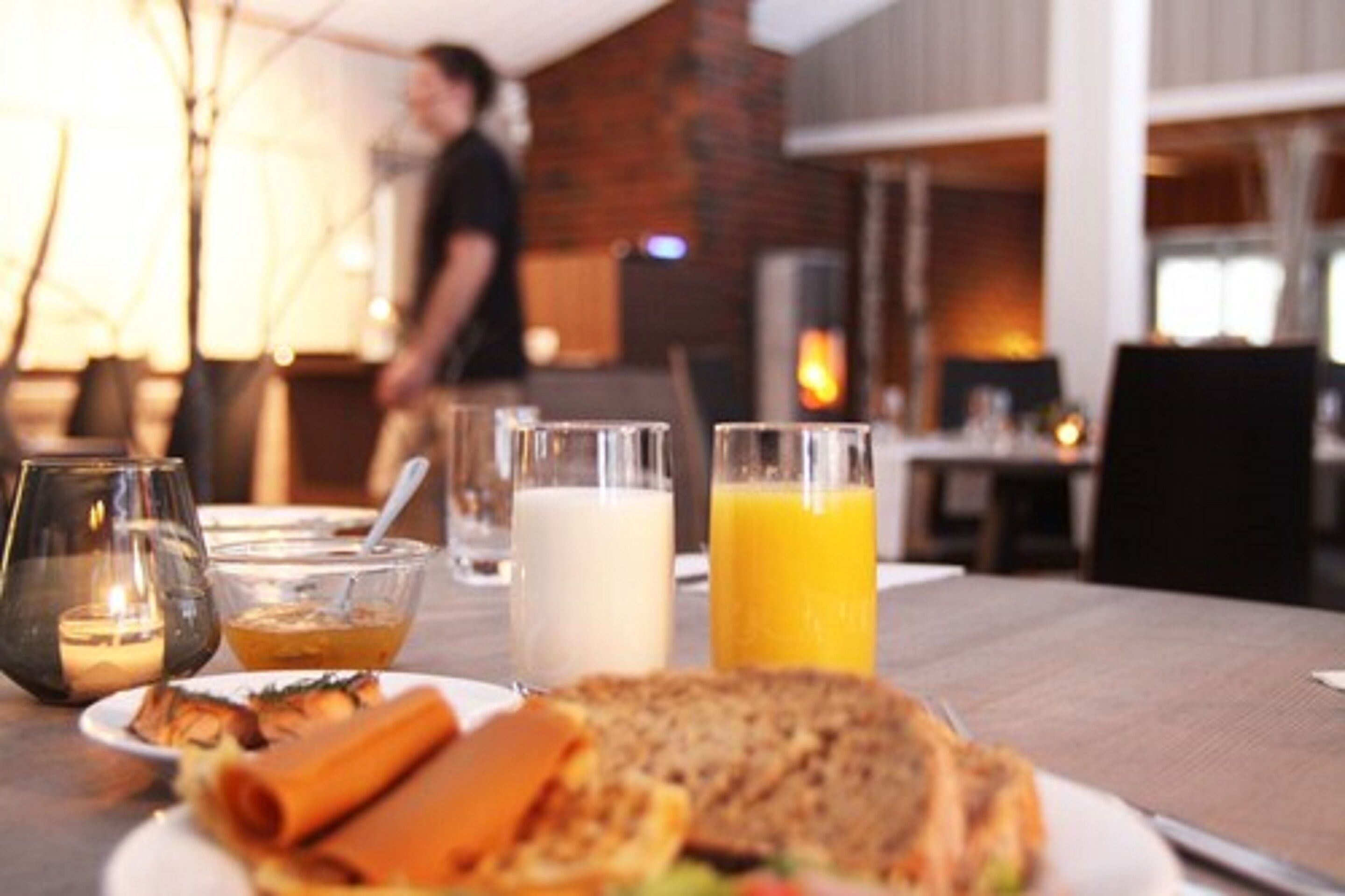 A breakfast setting with a plate of food, a glass of milk, and a glass of orange juice on a table.