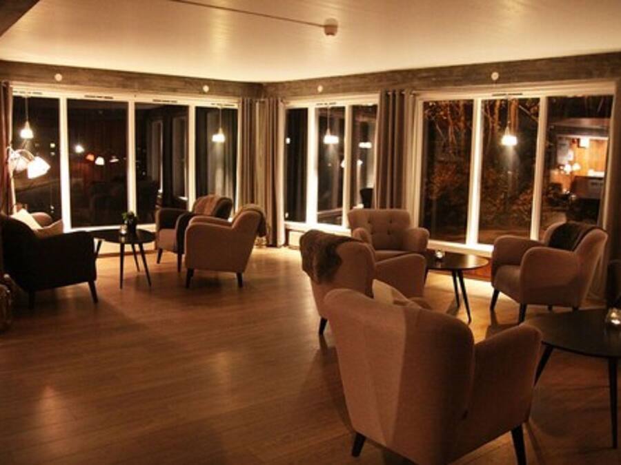 Um quarto espaçoso com piso de madeira, vários espaços de estar e grandes janelas com vista para o exterior.