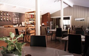 Een modern restaurant met een bar, houten meubels en een krijtbordmenu.