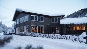 Un moderno edificio de dos pisos con ventanas grandes y un techo cubierto de nieve.