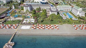 Vista aérea de um resort com praia, um píer e vários edifícios com piscinas.